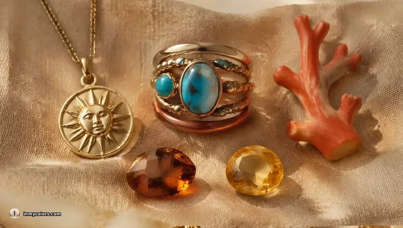 True Spring jewellery — yellow gold sun-face coin pendant, stacked rings with warm matrix turquoise, loose hessonite and citrine gems with coral branch on warm sandy fabric