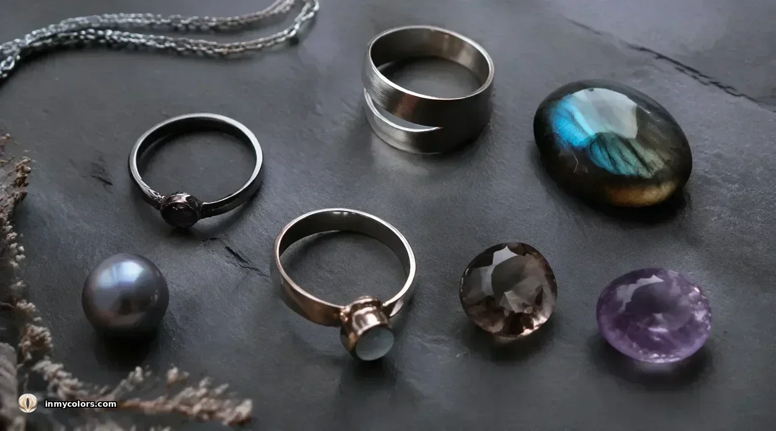Soft Summer jewellery — matte brushed silver rings, thin silver chains, labradorite stone, grey pearl, grey amethyst and moonstone on dark slate with dried botanicals